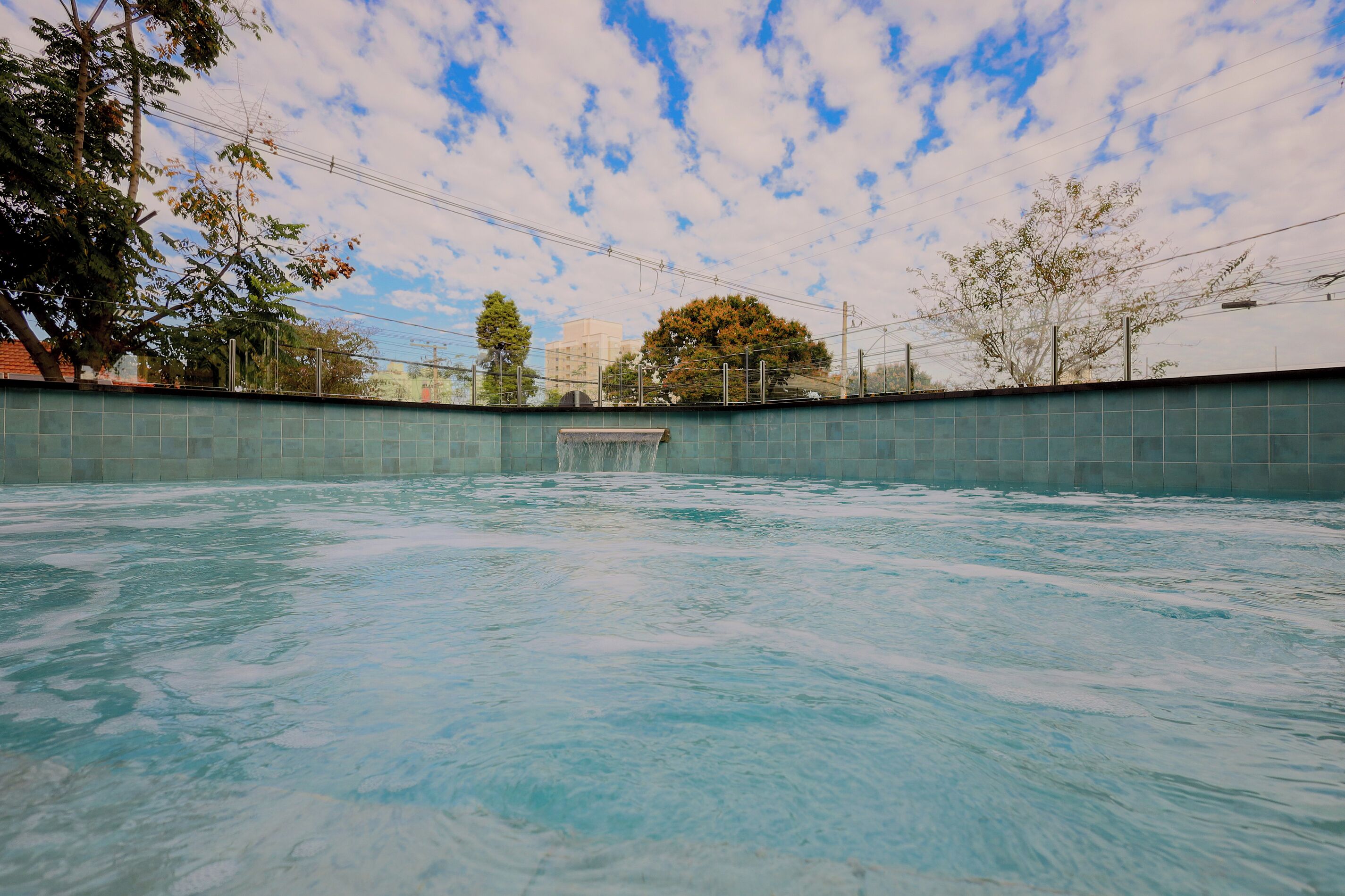 En swimmingpool med en kakelbeklädd vägg och en klar himmel ovanför.