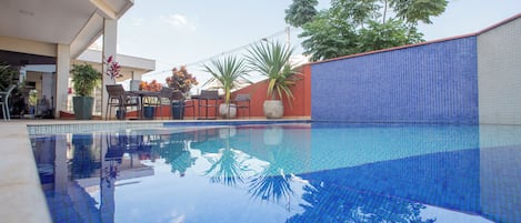 Una piscina al aire libre, sillones reclinables de piscina