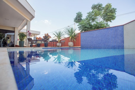 Una piscina al aire libre, sillones reclinables de piscina