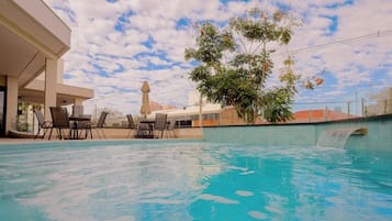 Una piscina al aire libre, sillones reclinables de piscina