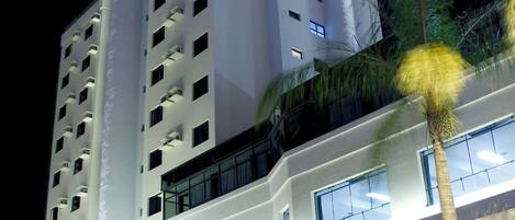A modern hotel with a prominent 'HOTEL' sign, multiple floors, and a well-lit entrance.