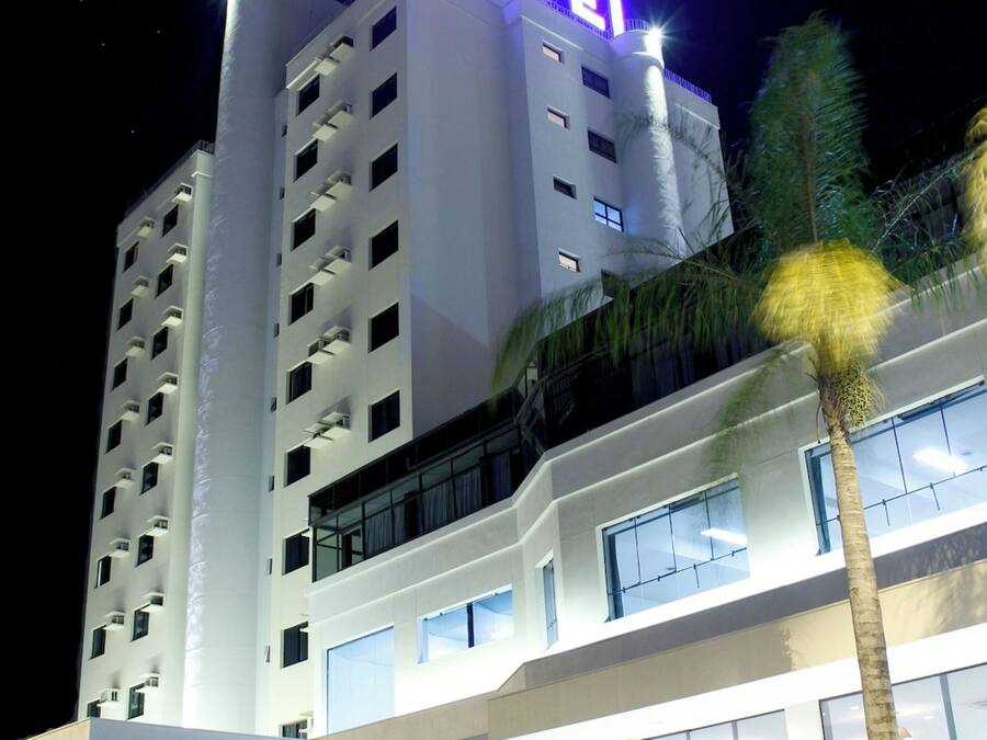 Un hotel moderno con un llamativo letrero que dice 'HOTEL', varios pisos y una entrada bien iluminada.