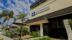 Exterior del Hotel Antonio’s Palace, con cielo despejado, palmeras y un diseño arquitectónico moderno.