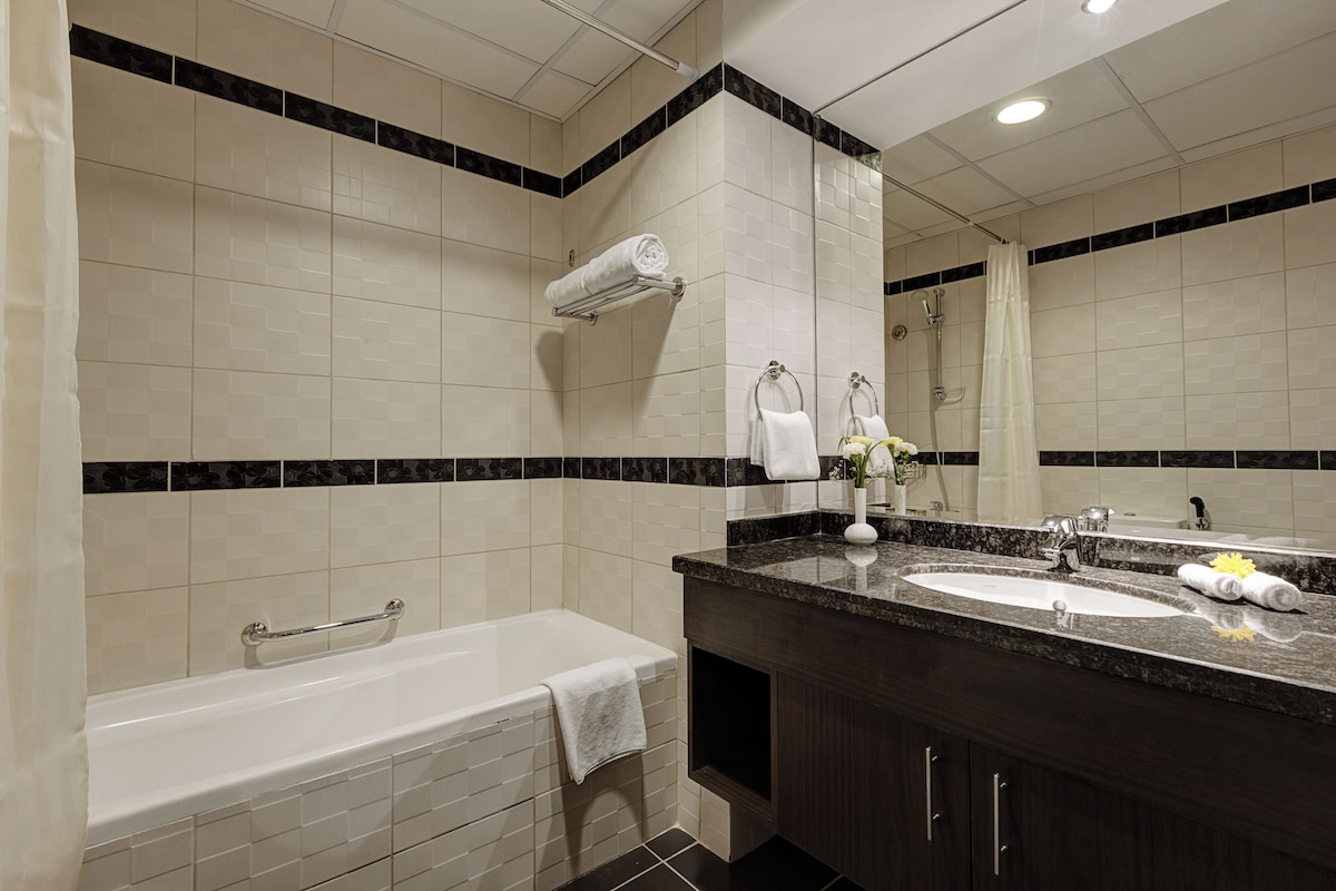 A modern bathroom with a bathtub, two sinks, and a large mirror.
