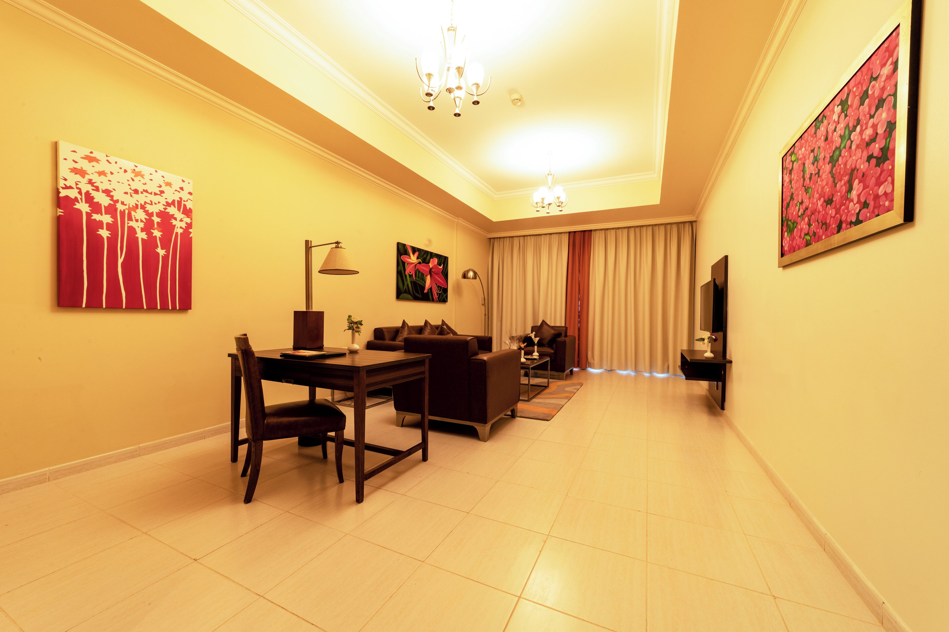 A living room with a dining area, a sofa set, a TV, and artwork on the walls.