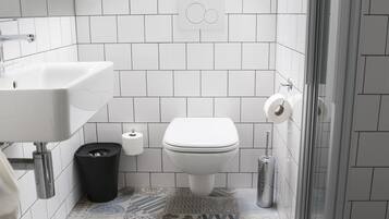 Ein modernes Badezimmer mit weißem Waschbecken, WC und Dusche. Der Boden ist mit gemusterten Fliesen ausgelegt, und über dem WC befindet sich ein Dachfenster.