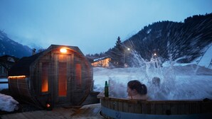 Une cabane en bois avec un petit porche et un jacuzzi.