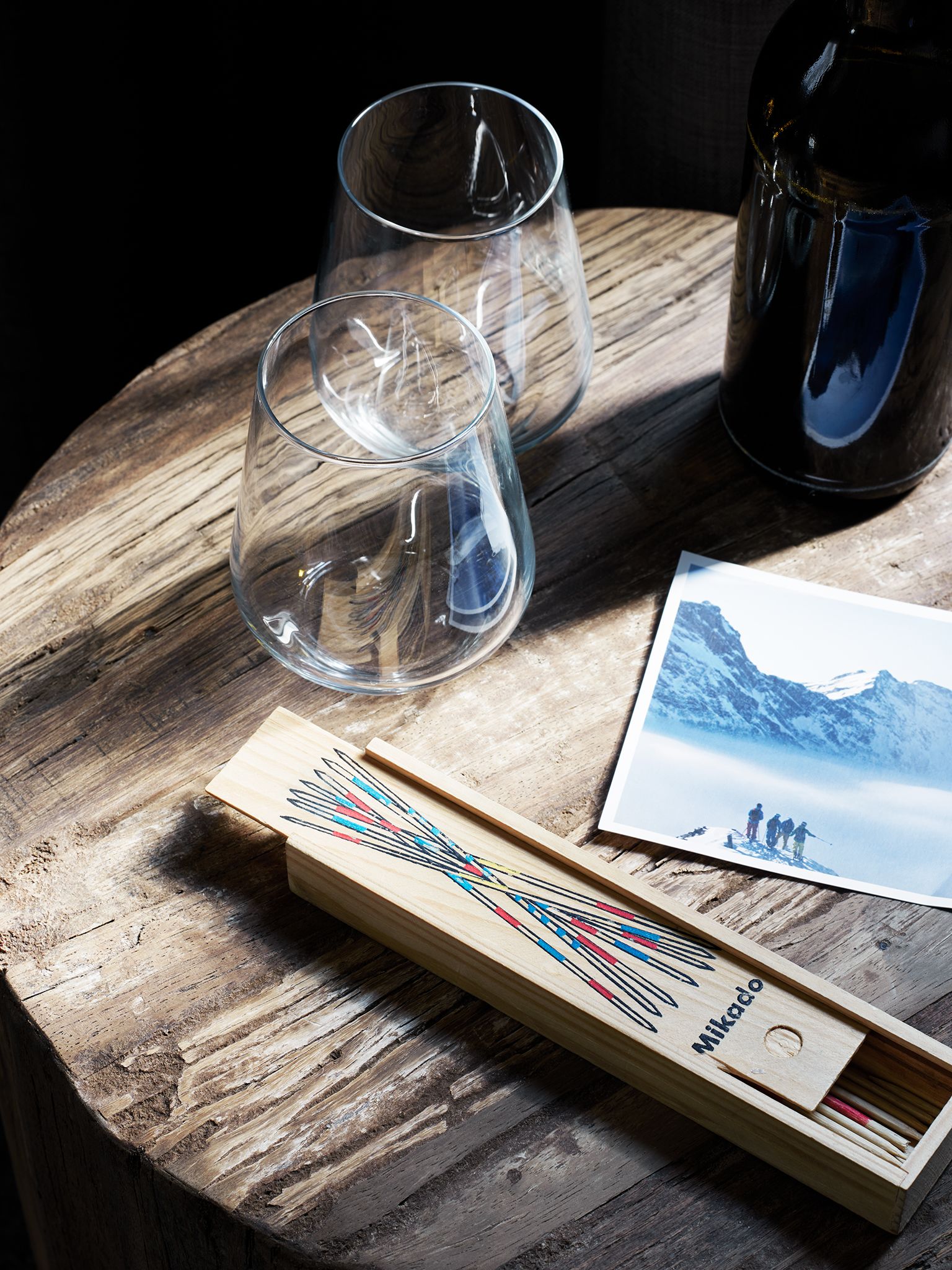 Una mesa de madera con dos vasos transparentes, una caja de cerillas y una fotografía.