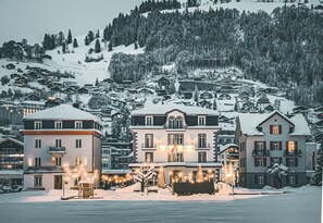 A snow-covered hotel with multiple stories, balconies, and a lit entrance.