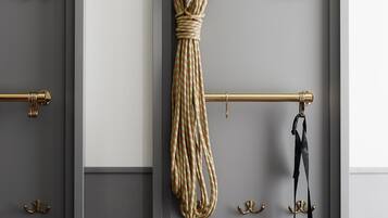 Une pièce avec une porte grise, une poignée de porte en laiton et une barre à serviettes en laiton sur laquelle sont accrochés une serviette et un sac.