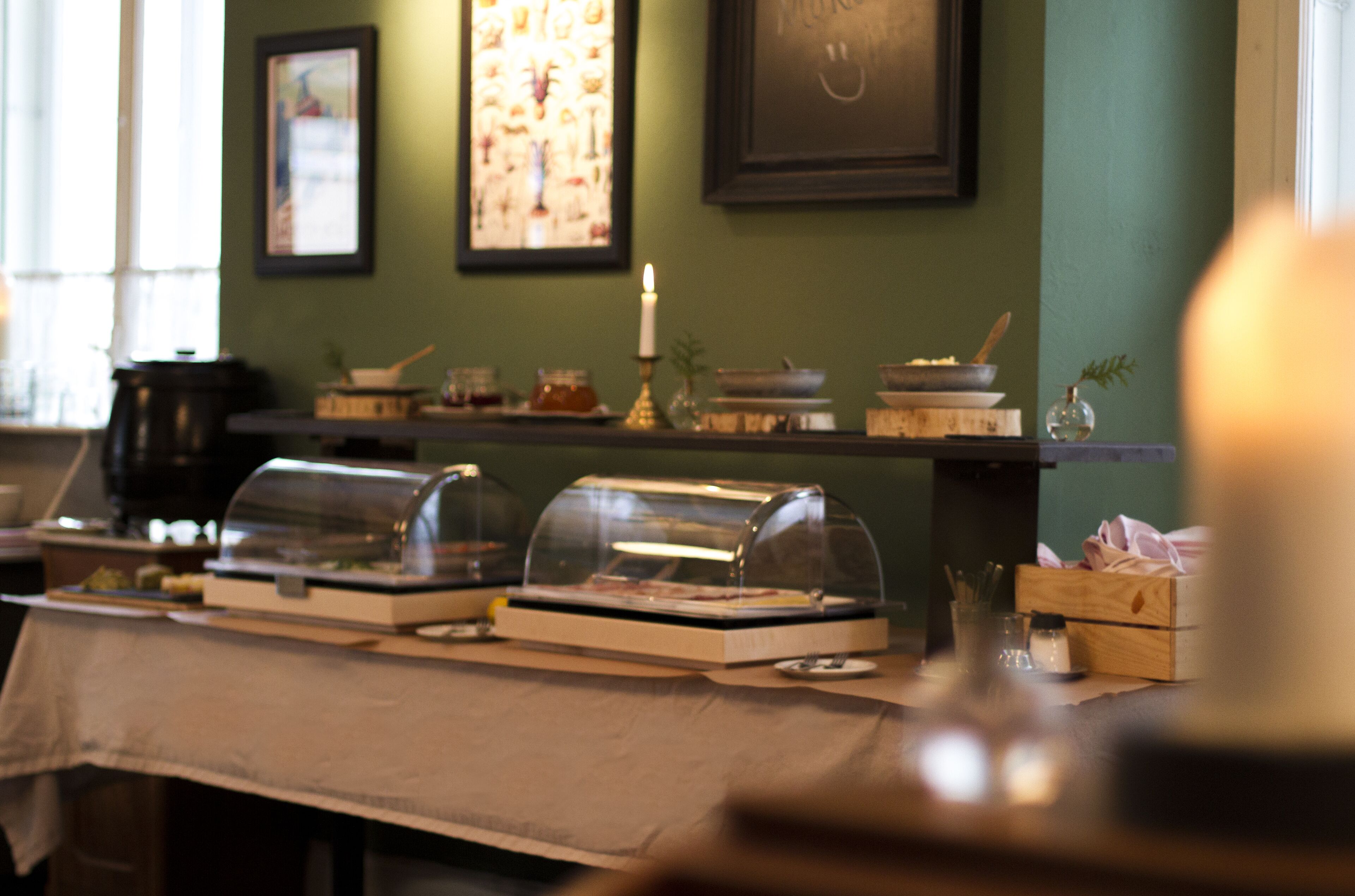A buffet setup with covered food displays and a candle on a table.