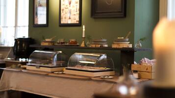 A buffet setup with covered food displays and a candle on a table.