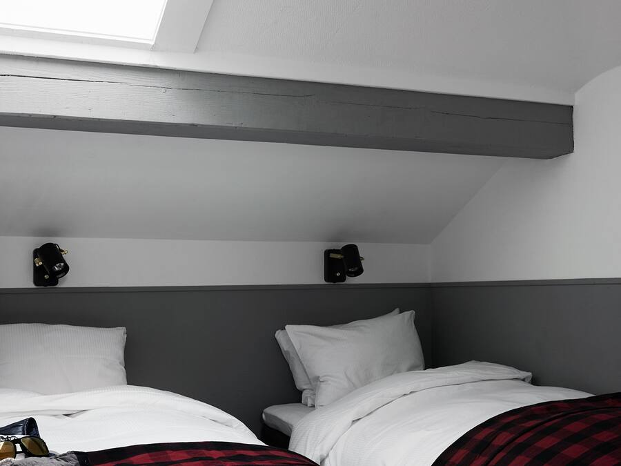 Habitación con dos camas, tragaluz y cabecero gris.