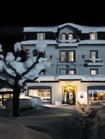 A large, multi-story building with snow-covered balconies and a well-lit entrance.