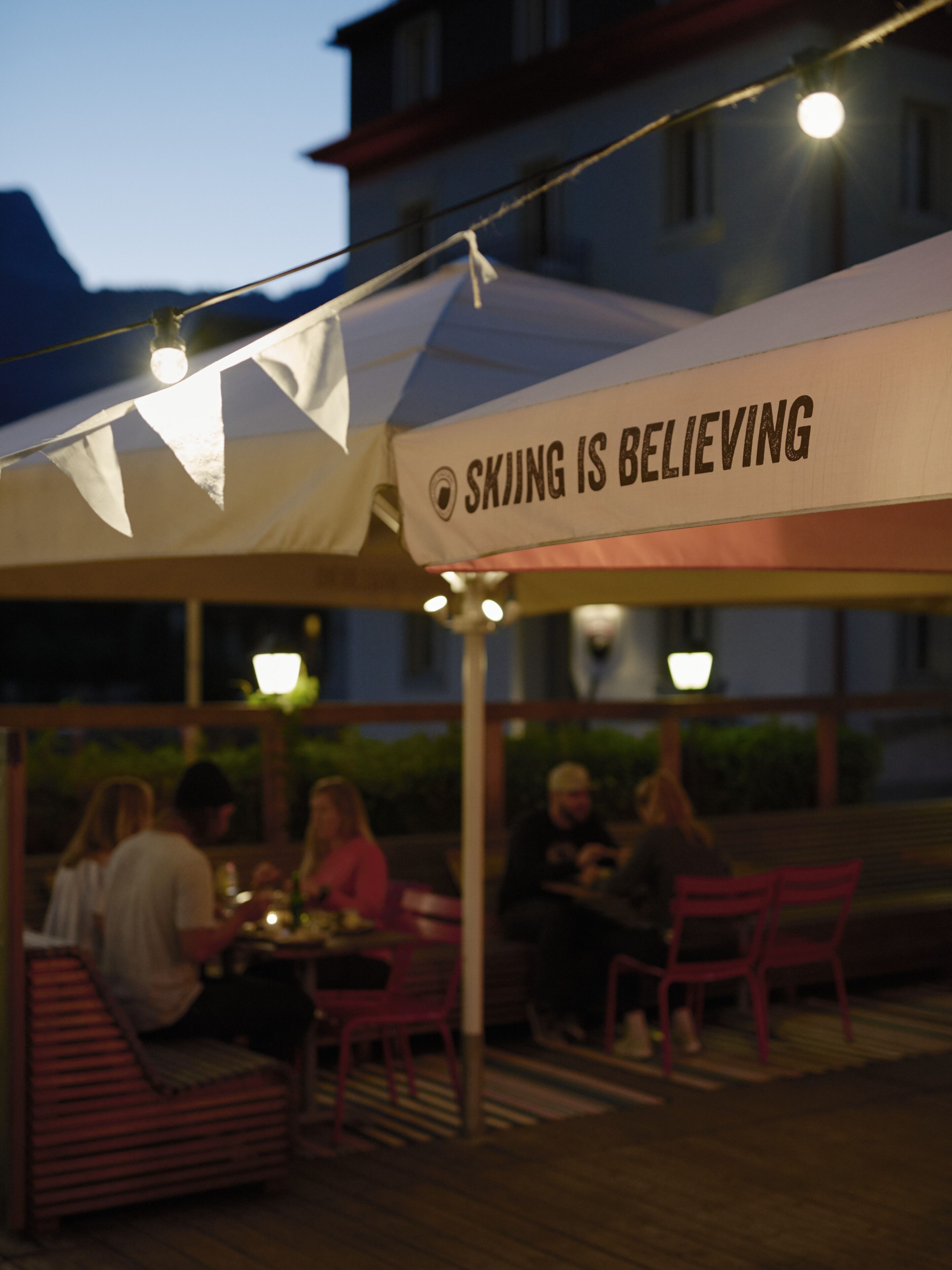 An outdoor seating area with a banner that reads "SKIJING IS BELIEVING".