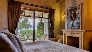 A bedroom with a large bed, a fireplace, and a view of the outdoors. - Six Keys Seaside Lodge (South Pelion)