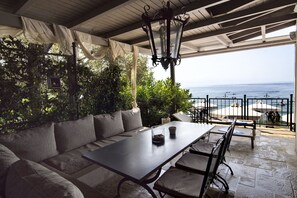 A covered outdoor seating area with a table and chairs, overlooking the sea. - Six Keys Seaside Lodge (South Pelion)