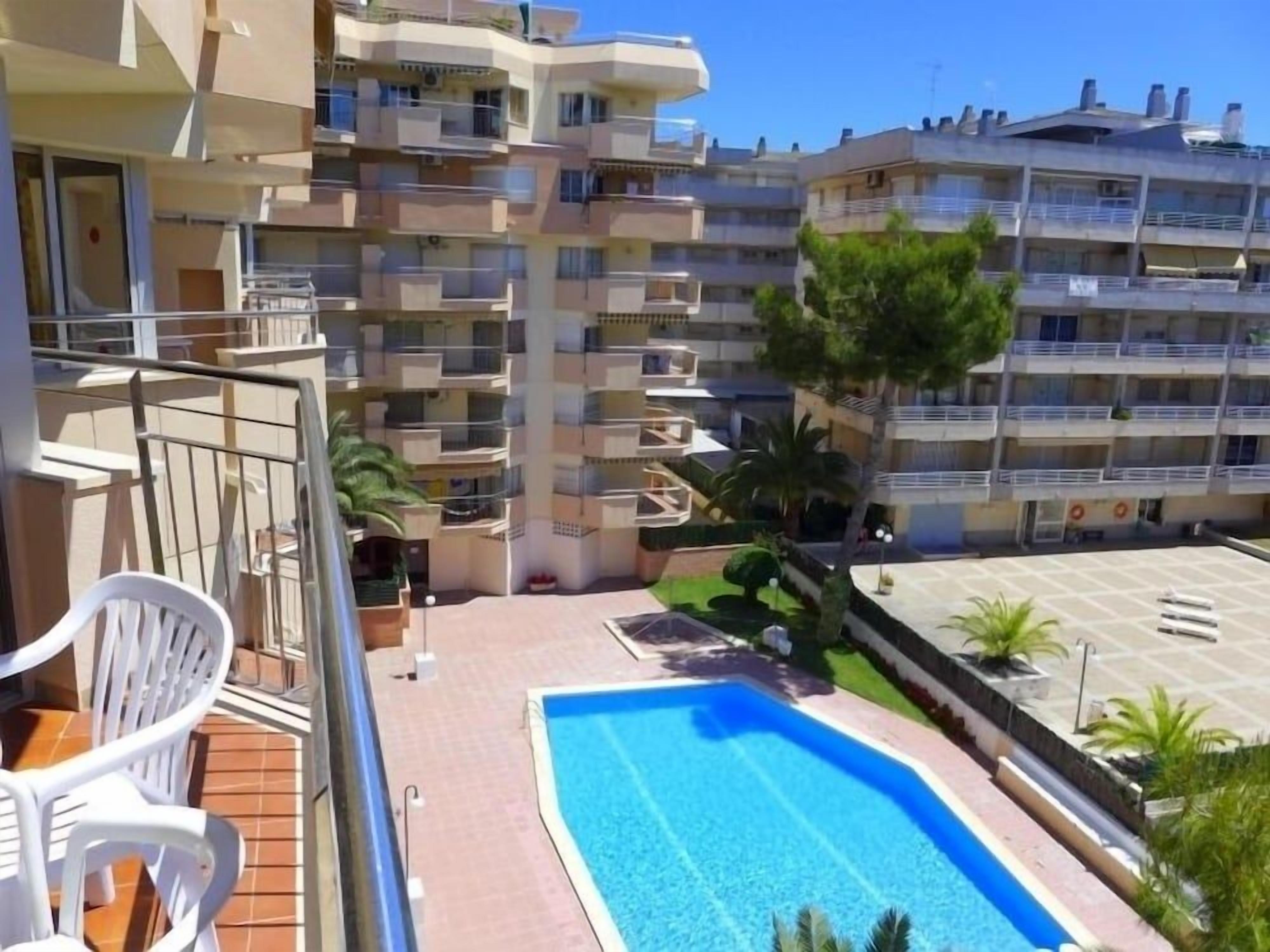 A residential building with multiple balconies, a swimming pool, and a small garden area.