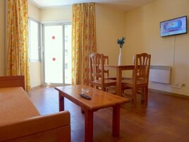 Una habitación con una cama, una mesa de madera y un televisor montado en la pared.