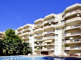 Un hotel de varios pisos con balcones, piscina y palmeras.