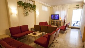 Un vestíbulo de hotel con sofás rojos, un televisor y una planta.
