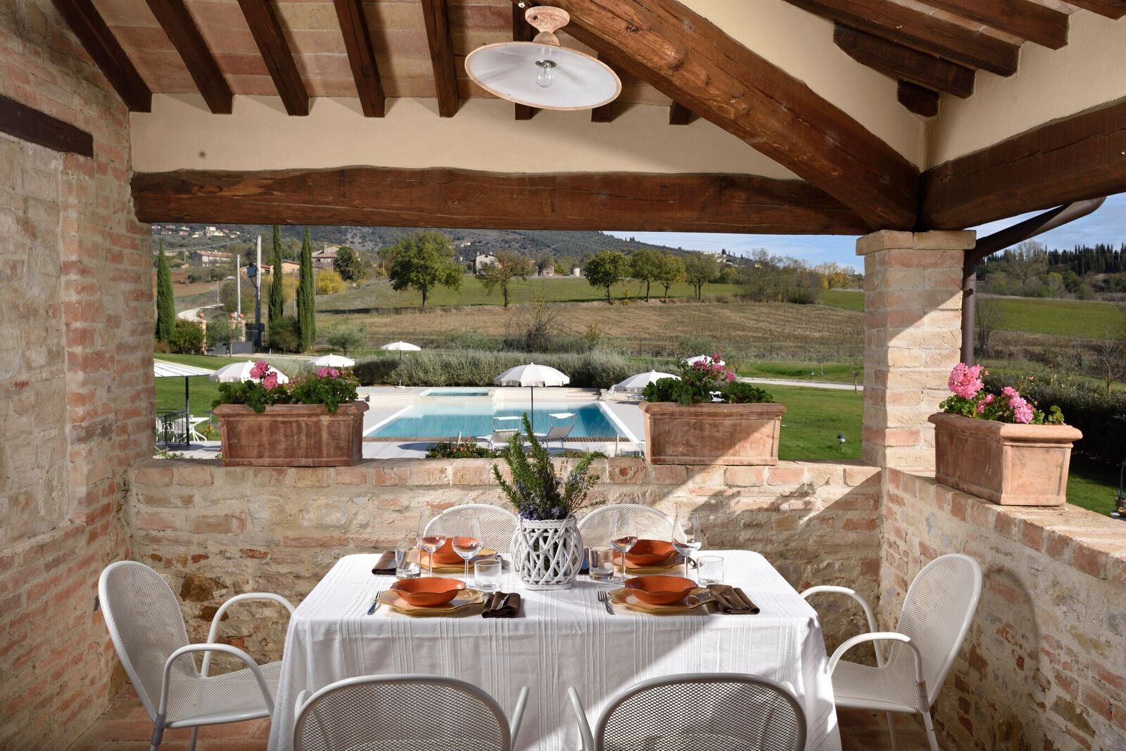 Une terrasse extérieure avec une table dressée pour le repas, offrant une vue sur une piscine et un paysage pittoresque.