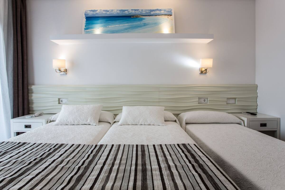 Ein Hotelzimmer mit einem großen Bett, zwei Nachttischen, einem Wandbild und zwei Wandleuchten.