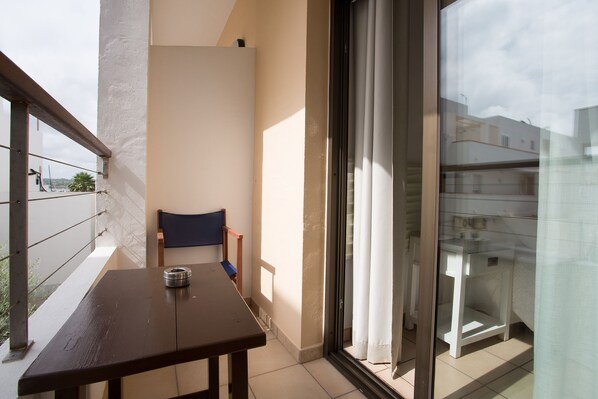 A balcony with a table, chair, and a view of the cityscape.