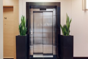 An elevator with a metallic finish, flanked by two potted plants. - Jovi Apartments (Sopot)
