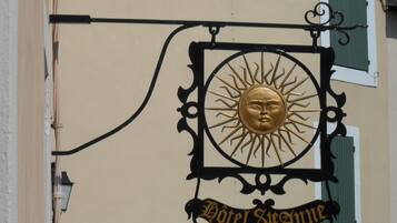 Une enseigne murale ornée d’un motif solaire et portant l’inscription « Hôtel Steamerme ».