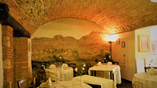 A restaurant with brick walls and a vaulted ceiling, featuring round tables set for dining. - Hotel La Rocca (Narni)