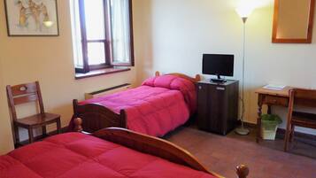 Une chambre avec deux lits, un bureau, une chaise, une télévision et une fenêtre avec des rideaux.