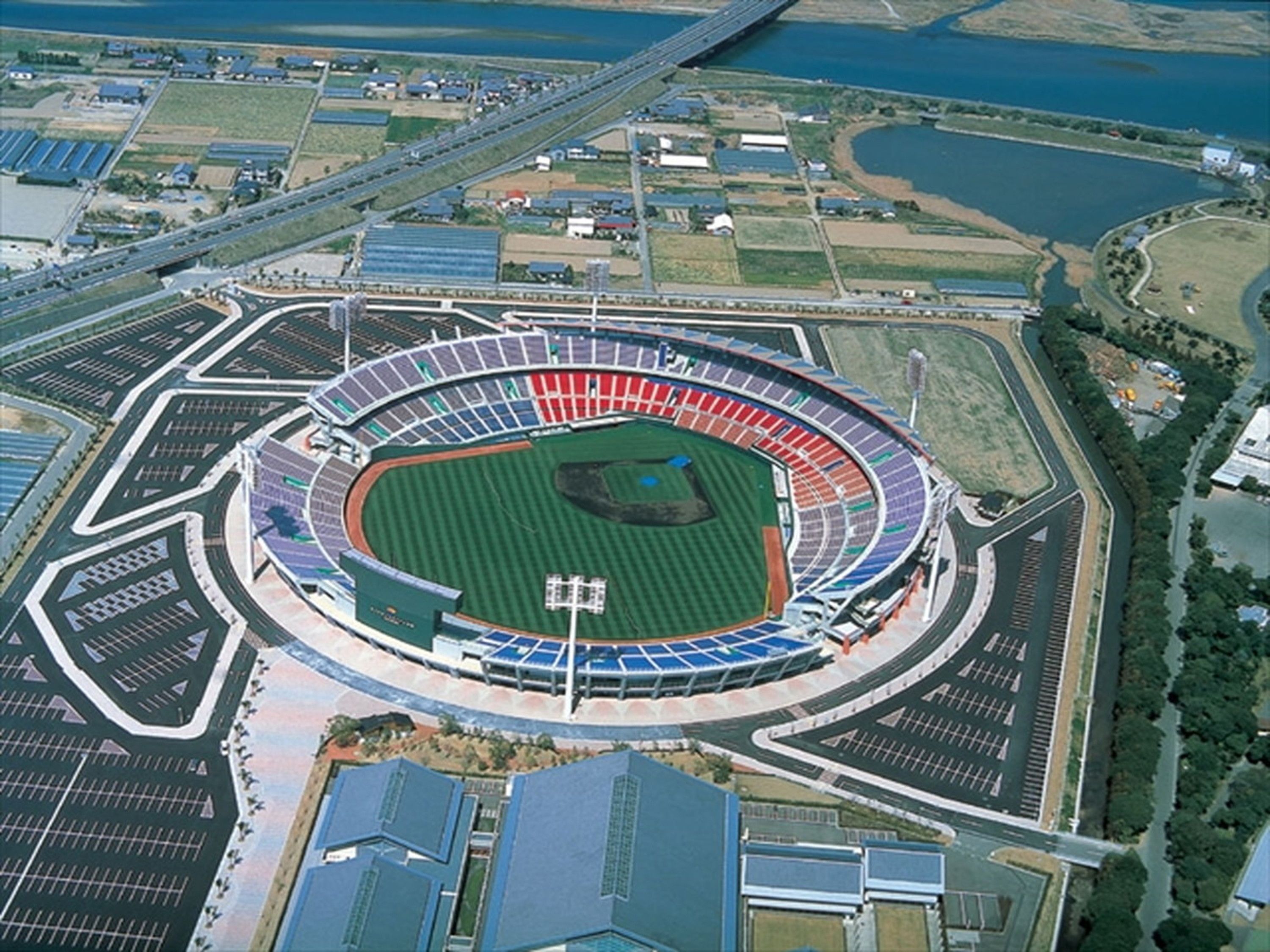 Un estadio con un campo central, asientos alrededor y un puente al fondo.
