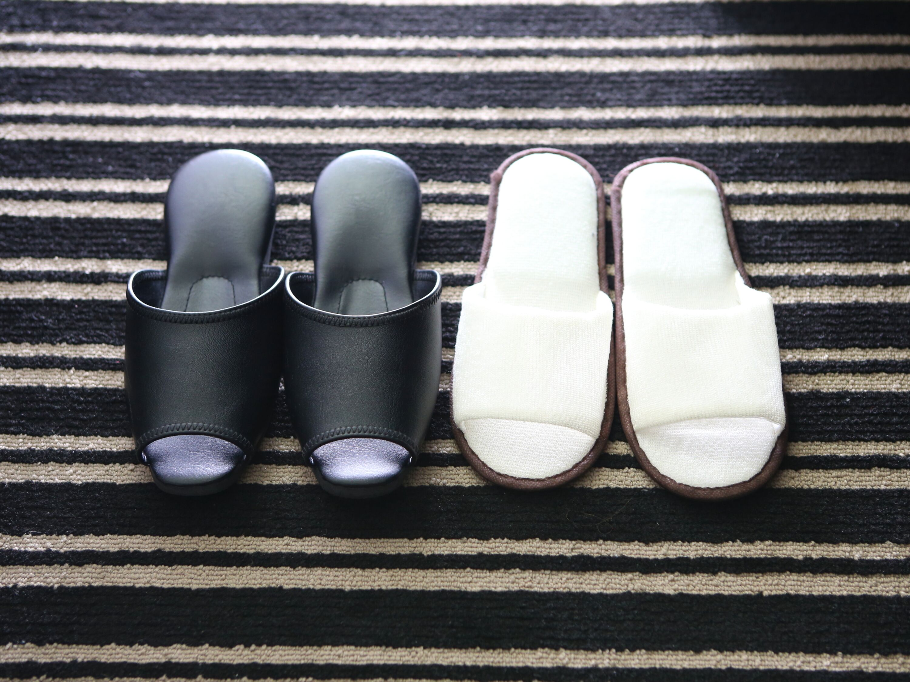 A pair of black and white slippers on a striped fabric.