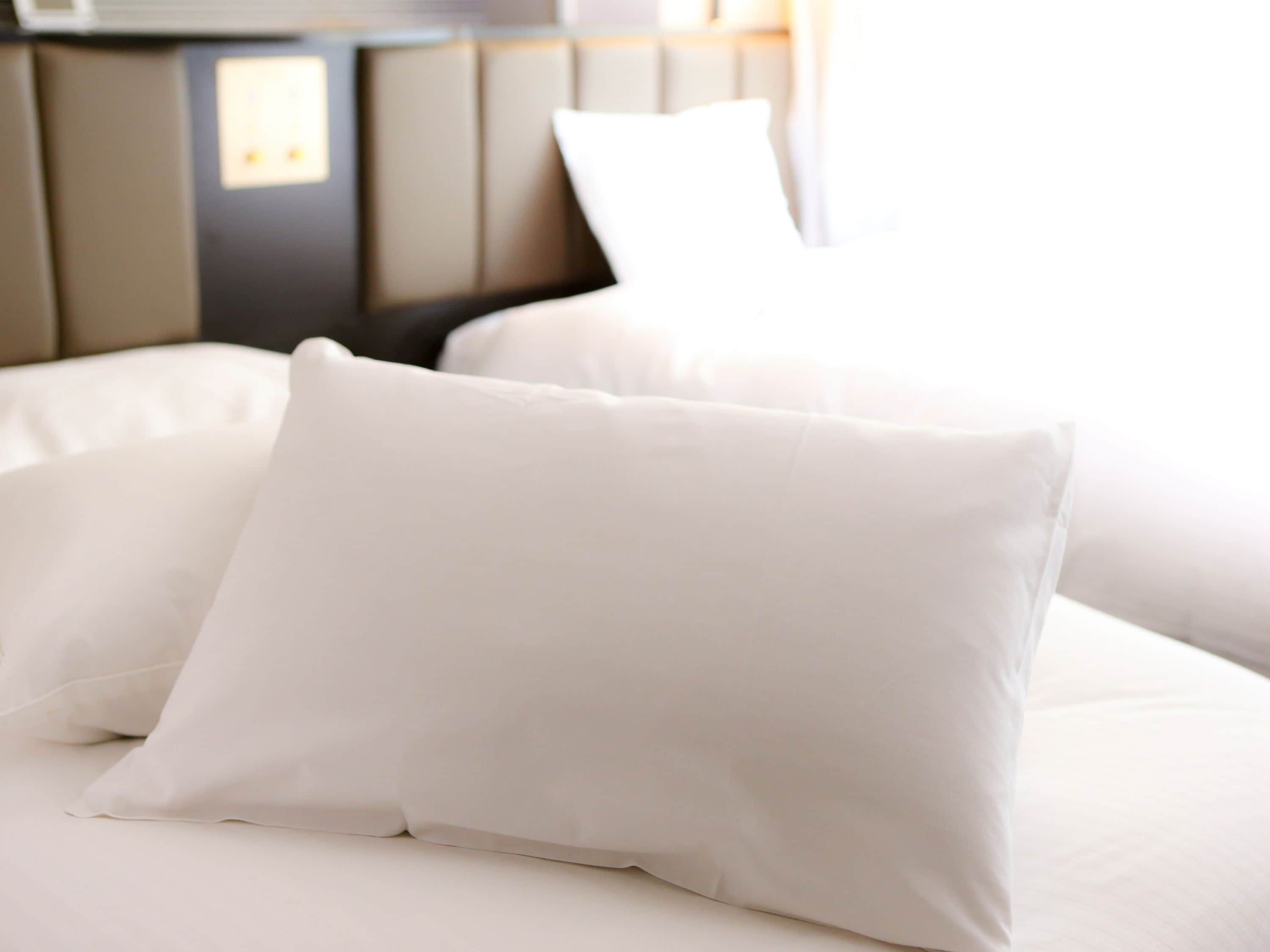 A bed with white bedding and a headboard.