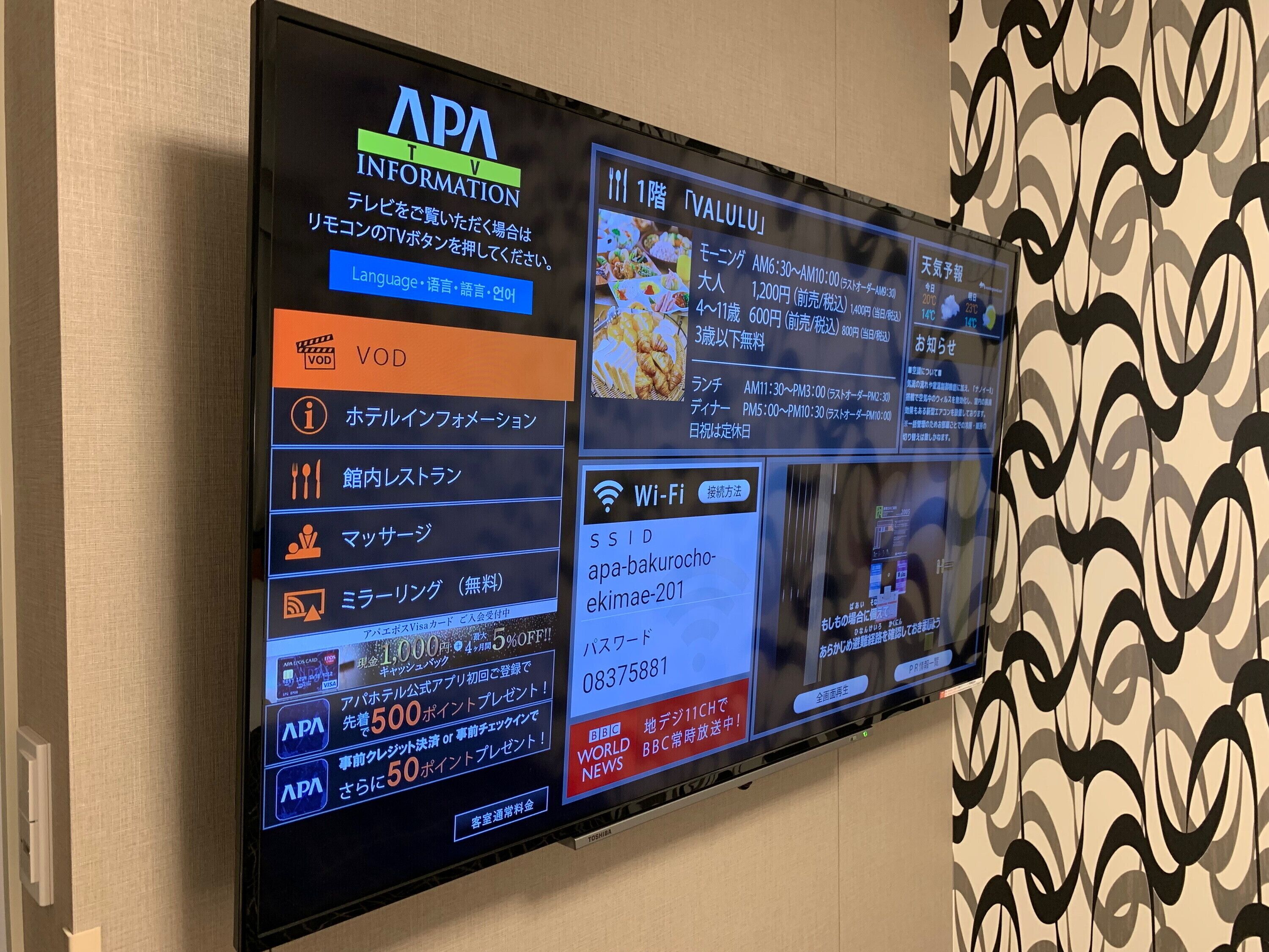 Una pantalla digital muestra información sobre servicios y comodidades, incluyendo una sección de Wi-Fi, un menú de restaurante y ofertas promocionales.