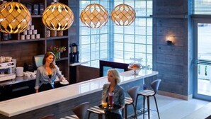 Een moderne hotel lobby met een receptiebalie, bar en zithoek.