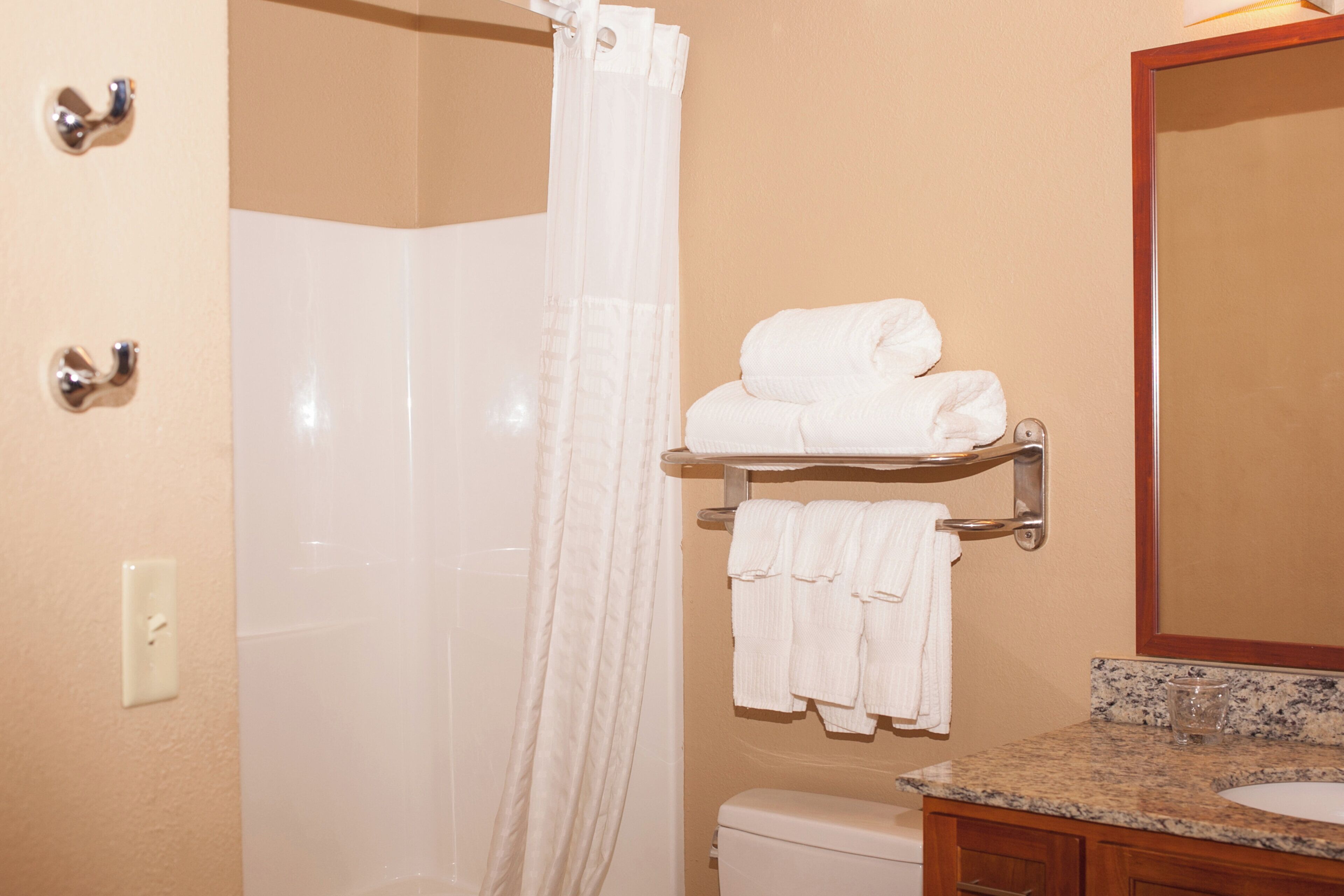 A bathroom with a shower, a toilet, a sink, and a towel rack with towels.