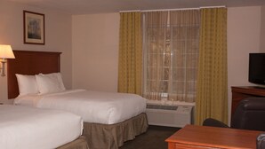 Hotelkamer met twee bedden, een bureau, een stoel, een televisie en een raam met gordijnen.