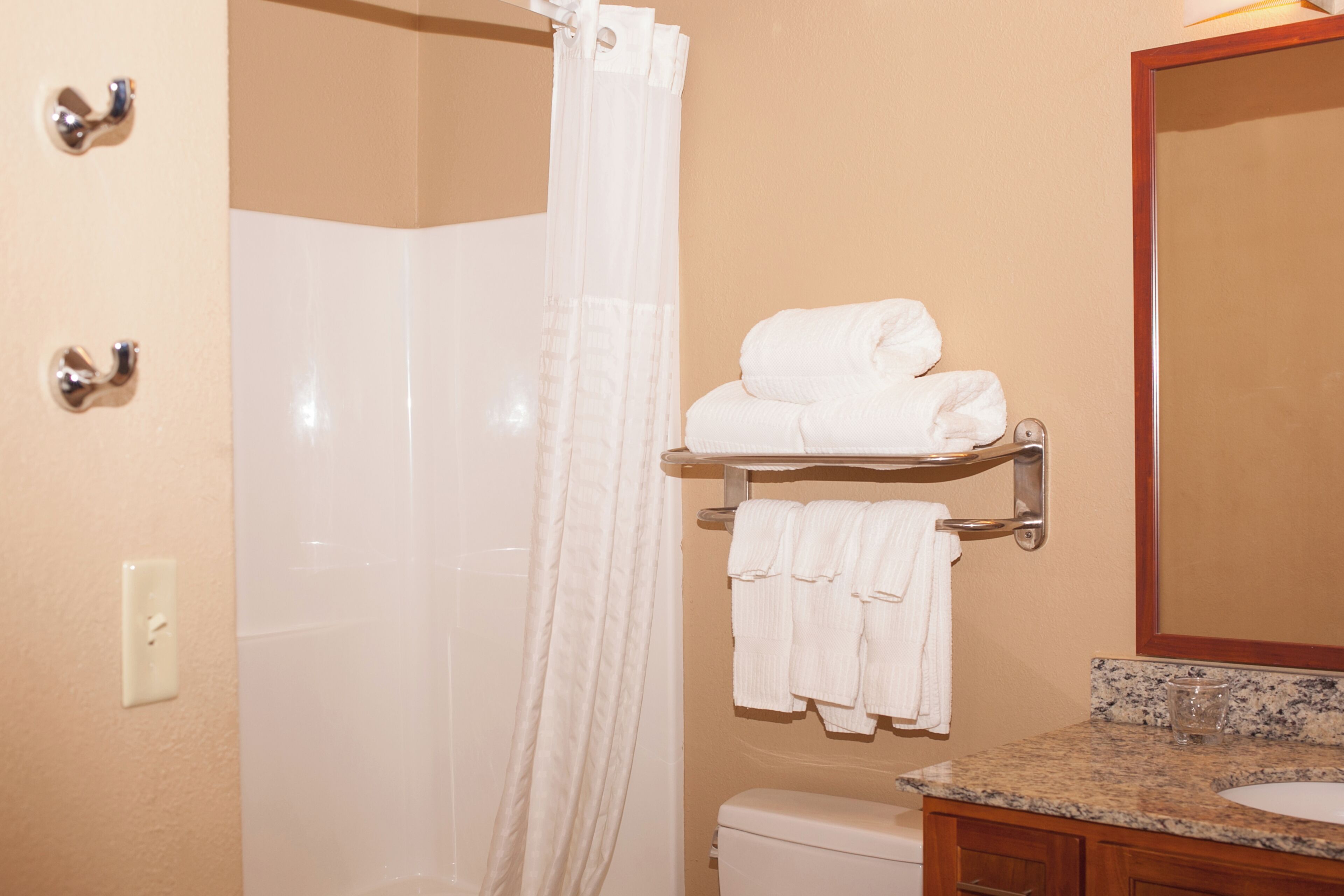 A bathroom with a shower, a toilet, a sink, and a towel rack with towels.
