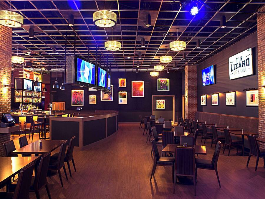 Un ristorante con area bar, diverse televisioni e opere d'arte incorniciate alle pareti.