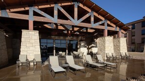 A covered outdoor area with lounge chairs and a stone wall.