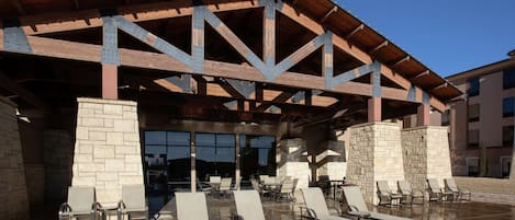 A covered outdoor area with lounge chairs and a stone wall.