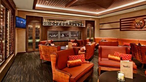 A hotel lobby with a bar area, leather sofas, and a television screen.