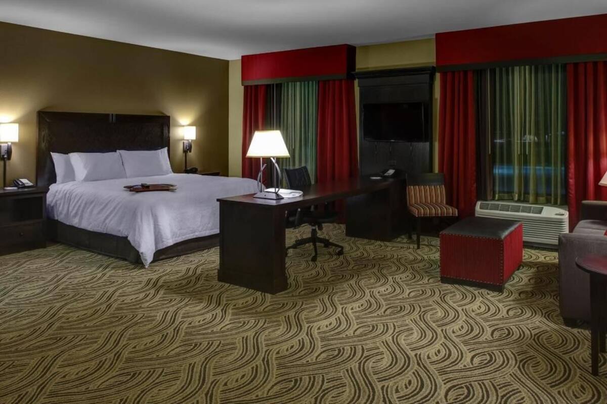 Ein Hotelzimmer mit Bett, Schreibtisch, Stuhl und Fernseher.