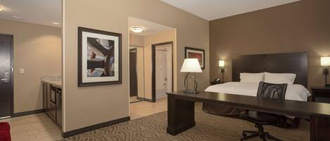 A hotel room with a bed, desk, chair, and a large mirror.