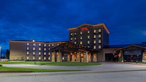 A hotel with a modern design, featuring a prominent entrance with a covered walkway and a sign that reads "Hampton Inn & Suites."