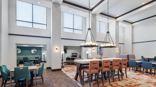 A spacious dining area with high ceilings, large windows, and a mix of wooden and upholstered chairs.