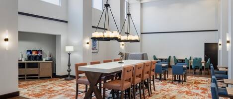 A spacious conference room with a long table, multiple chairs, and pendant lighting.