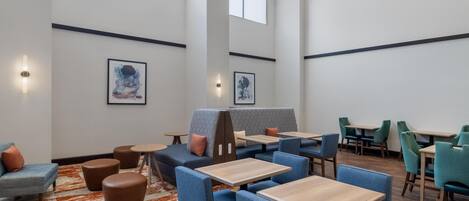 A modern interior with seating arrangements, tables, and artwork on the walls.